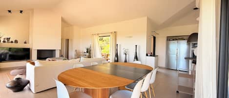 A modern living space with a dining area, kitchen, and a television.