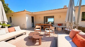 An outdoor patio with a sofa, chairs, a table, and umbrellas. - Villa A Muredda Di Olmuccio (Zonza)