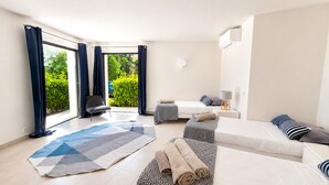 Et moderne hotelværelse med stort vindue, sofa, seng, stol og lille bord.