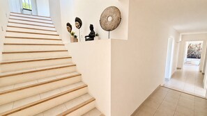 Eine moderne Treppe führt zu einem Flur mit einer großen, runden Wanddekoration und einer Statue.
