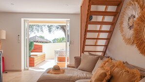Een moderne woonkamer met een bank, een ladder en uitzicht op de omgeving.
