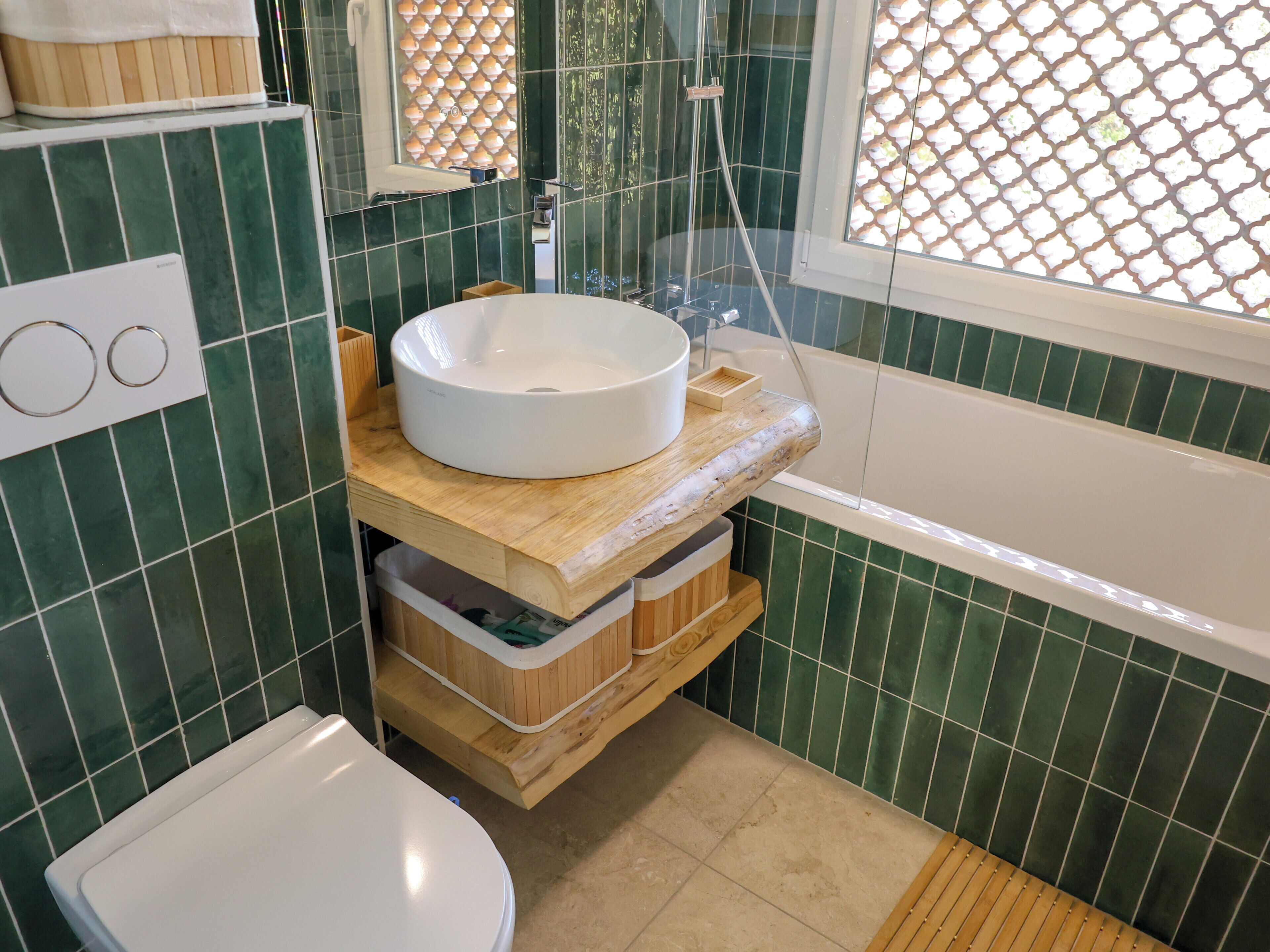 A bathroom with a white sink, wooden vanity, and a bathtub.