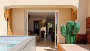 Een hotelkamer met een zwembad, een houten bank en een grote groene cactus.