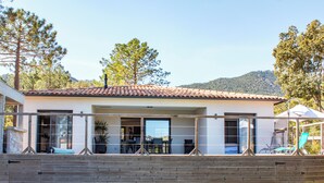 A modern house with a patio area, large windows, and a view of the surrounding landscape. - Casa Cavu di Santa Lucia (Zonza)