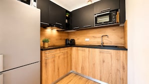 Eine kompakte Küche mit Holdekor-Schränken, einer schwarzen Arbeitsplatte, einem eingebauten Backofen und einem Spülbecken.