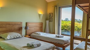 A room with two beds, a window, and a view of greenery. - Villa A Pinedda Mare (Zonza)