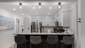 A modern kitchen with a central island, bar stools, stainless steel appliances, and recessed lighting. - NEW! Ski, Sauna, Jacuzzi, Nintendo, Game Room, Fireplace (Brian Head)