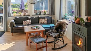 Een gezellige woonkamer met een bank, een schommelstoel, een houten tafel en een open haard.