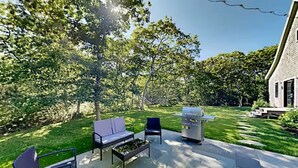 Une terrasse extérieure équipée d’un barbecue, de sièges et d’une pelouse bien entretenue.