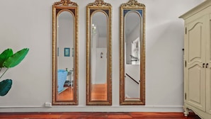 Three ornate mirrors with gold frames on a wall, a wooden floor, and a white cabinet to the right. - Gorgeous New York-Style Loft with Deck and Air-con (Auckland Central Suburbs)