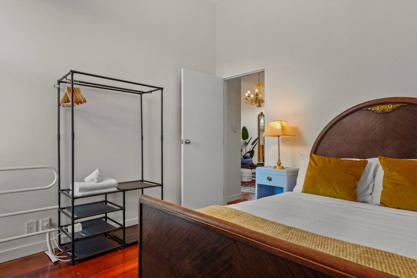 Une chambre d’hôtel avec un lit en bois, un lit superposé en métal, une table de chevet avec une lampe et un miroir au mur.