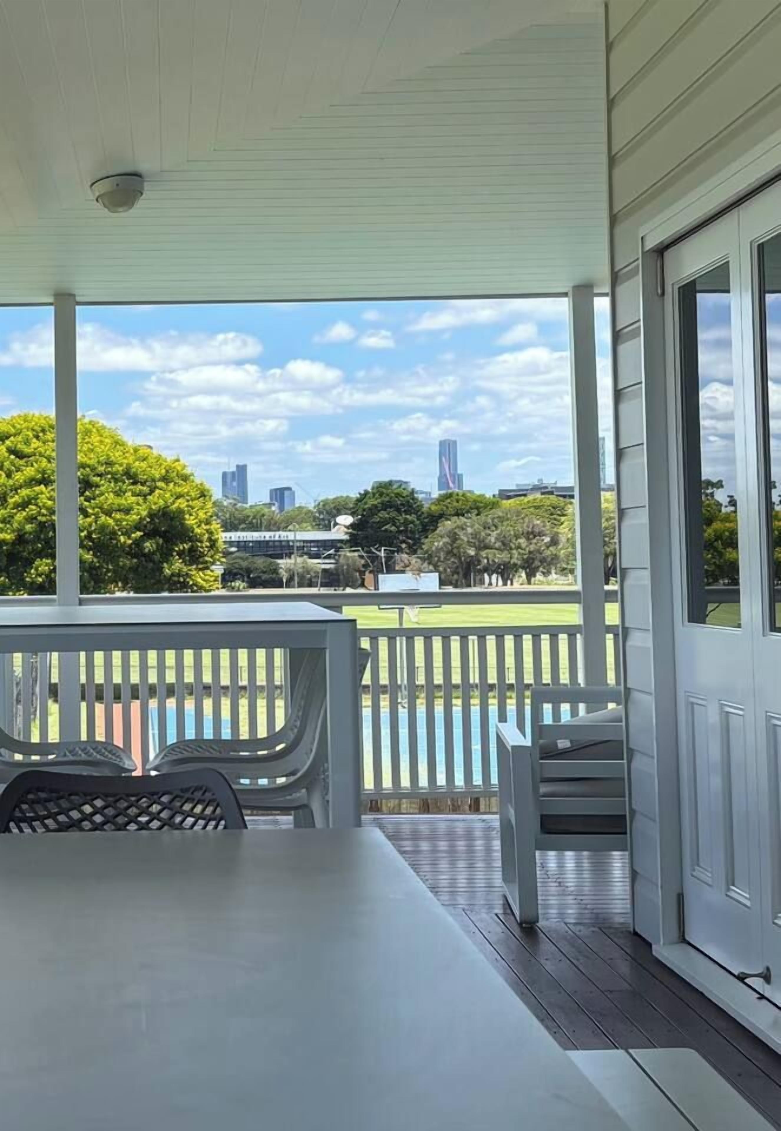 A covered outdoor area with a table and chairs, a view of a park and city skyline.