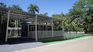 A covered outdoor area with a small building, a fenced area, and a green space. - Coqui Tiny House - Unit 12 (Rincón)