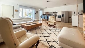 Ein modernes Wohnzimmer mit einer Couch, Sesseln, einem Couchtisch und einem Teppich.