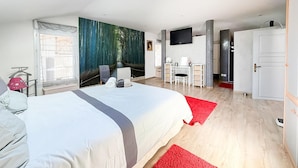 Ein Hotelzimmer mit Bett, Schreibtisch, Stuhl, Fernseher und Kleiderschrank.