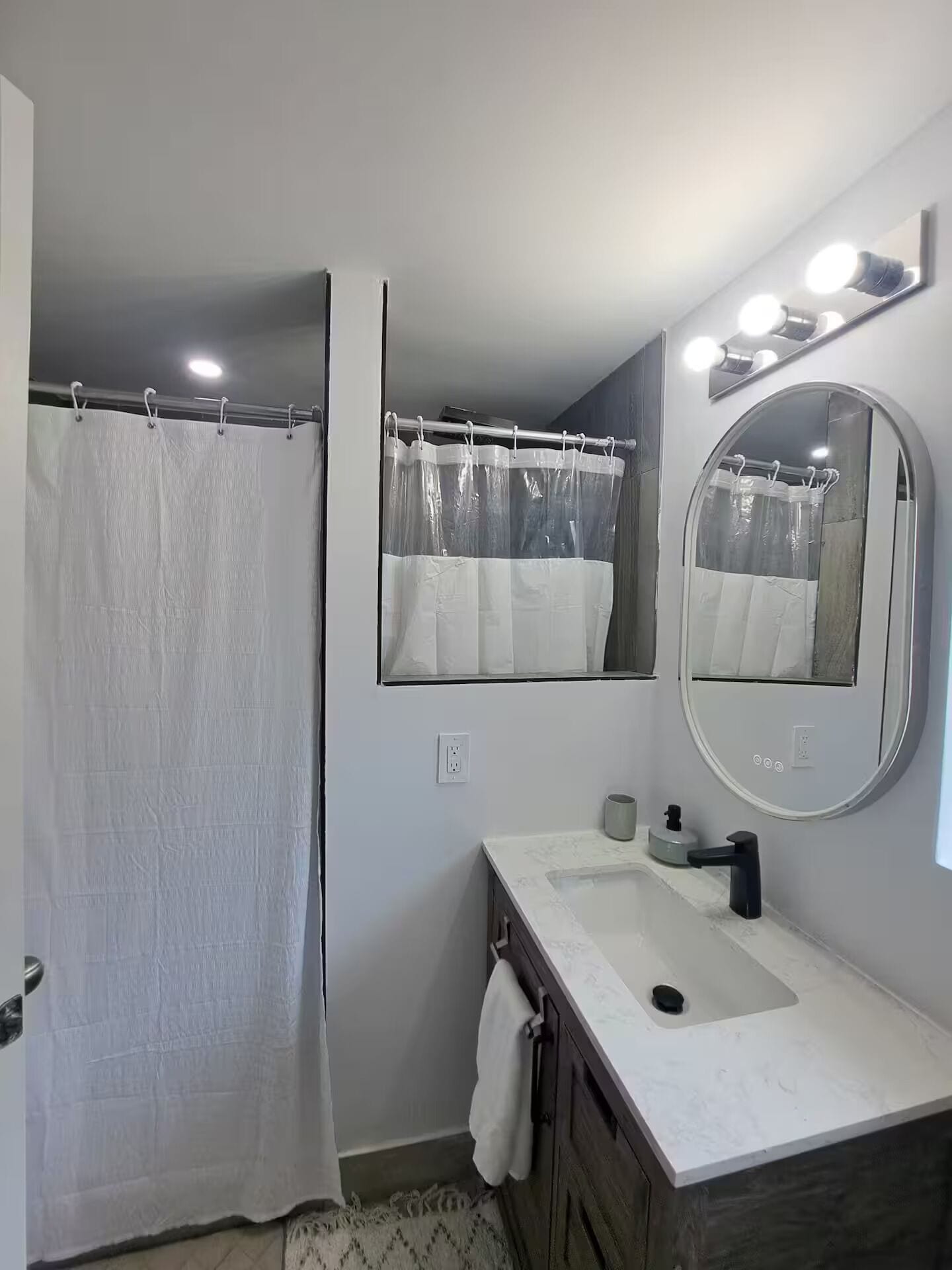 Une salle de bain avec un rideau de douche, un lavabo avec un miroir et un porte-serviettes.