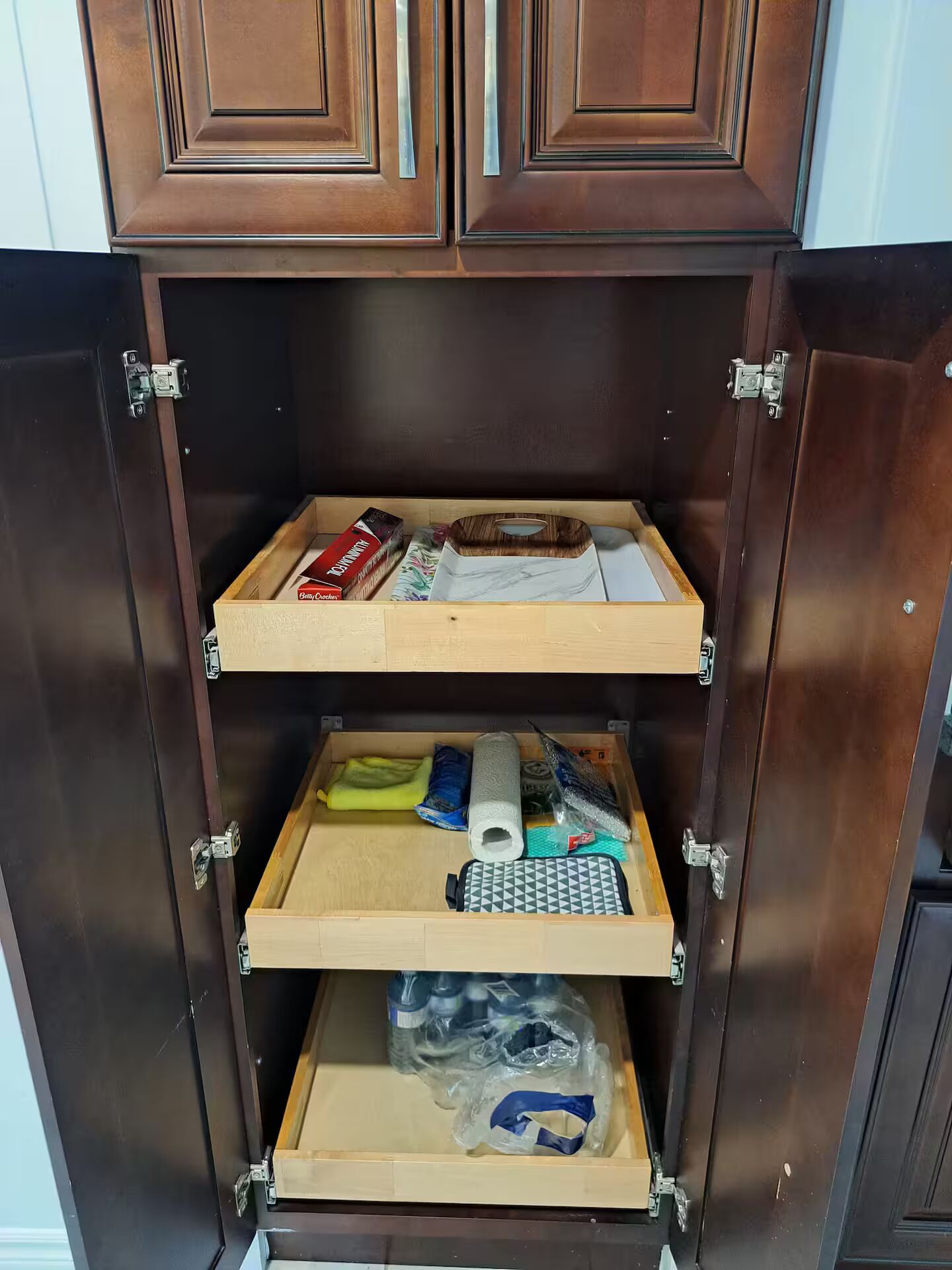 Ein Holzschrank mit drei Einlegebögen, der verschiedene Gegenstände wie eine Kiste, eine Rolle und eine Tüte beherbergt.