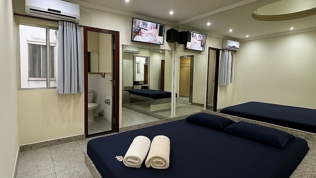 A hotel room with a bed, a TV, and a mirror. - Pousada La Castaña (Belém)