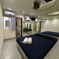 Quarto de hotel com cama, televisão e espelho.