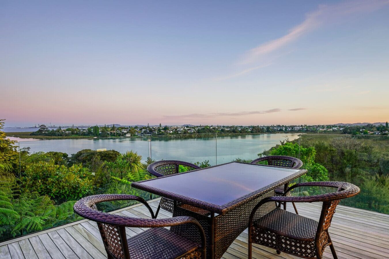 Een terras met tafel en stoelen met uitzicht op een waterpartij en een verre stadsgezicht.