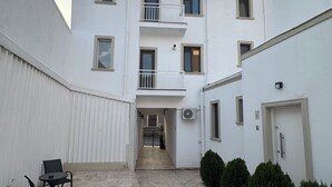 A courtyard with a white building, a small seating area with chairs, and a door marked with the number 5. - Velaris Downtown Retreat 24/7 Check-in (București)