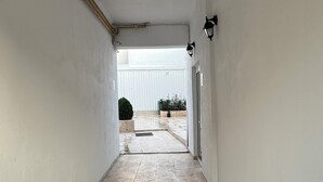 A corridor with tiled flooring, white walls, and a door leading to an outdoor area. - Velaris Downtown Retreat 24/7 Check-in (București)