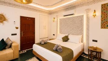 A hotel room with a bed, a sofa, a small table, and a decorative wall.
