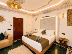 Une chambre d’hôtel avec un lit, un canapé, une petite table et un mur décoratif.