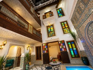 A traditional interior with ornate tile work, a balcony, and a seating area with a table and chairs. - Riad Dar Elbellar (Fes)