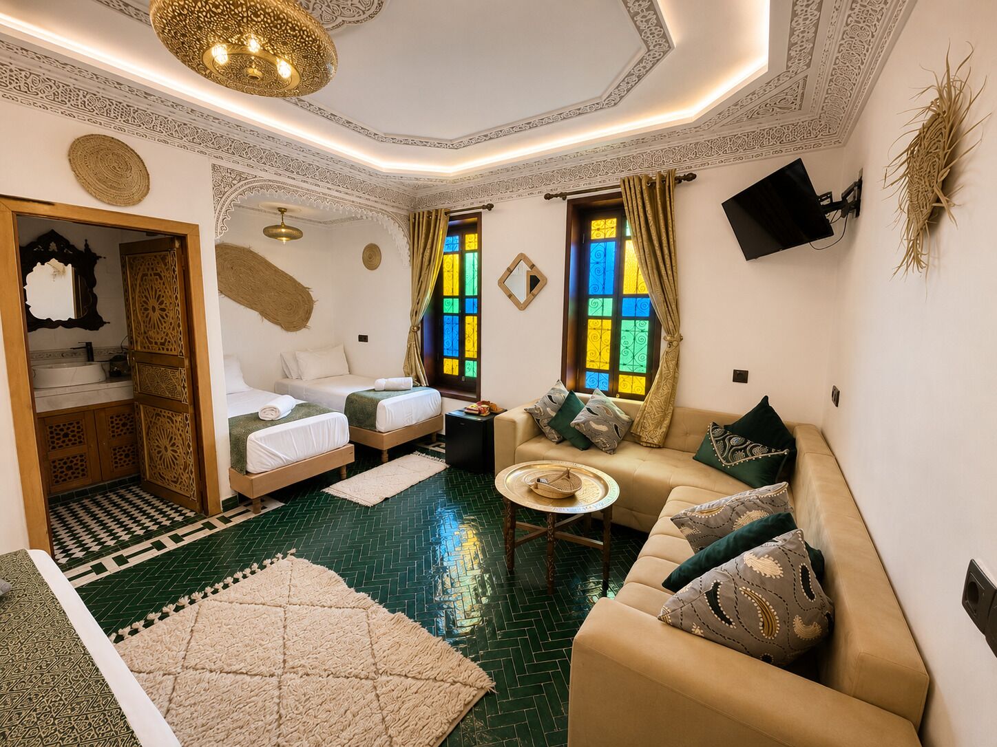 Une chambre avec deux lits, un canapé, une télévision et une petite table.