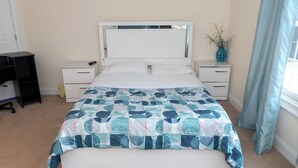 Une chambre à coucher comprenant un lit, des tables de chevet, une commode, un bureau et une fenêtre avec des rideaux.