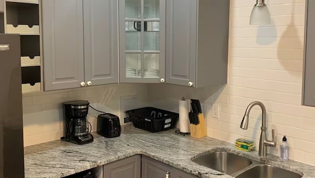 A modern kitchen with grey cabinets, a built-in wine rack, a coffee maker, and a sink. - Stunning Home Downtown with free street parking! Sleeps 10 (Columbus)