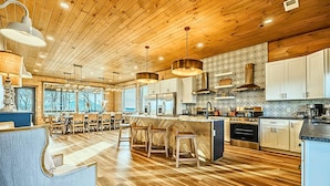 A modern kitchen with wooden flooring, pendant lighting, and white cabinetry. - Sleep 36 · Mega-Lodge w/ Indoor Pool & Mtn View (Sevierville)