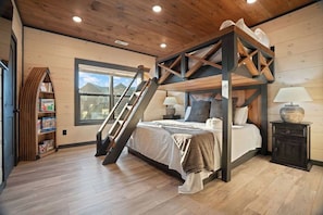 A bedroom with a wooden four-poster bed, a ladder, a bookshelf, and a window with a view. - Heated Indoor Pool · Hot Tub · Theater · Sleeps 20 (Sevierville)