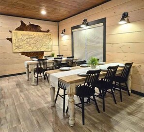 Un comedor con una gran mesa de madera, sillas negras y un mapa en la pared.