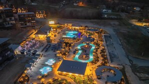 An aerial view of a resort with multiple swimming pools, outdoor seating areas, and well-lit pathways. - Heated Pool-Mtn View-Game Loft-Waterpark-Sleeps 20 (Sevierville)