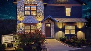 A two-story house with a stone facade and a well-lit entrance. - Heated Pool-Mtn View-Game Loft-Waterpark-Sleeps 20 (Sevierville)