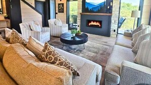 A spacious living room with a fireplace, comfortable seating, and a view of the outdoors. - Heated Pool-Mtn View-Game Loft-Waterpark-Sleeps 20 (Sevierville)