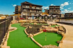 A miniature golf course with a green artificial turf, surrounded by stone walls and large rocks. - Heated Pool-Mtn View-Game Loft-Waterpark-Sleeps 20 (Sevierville)