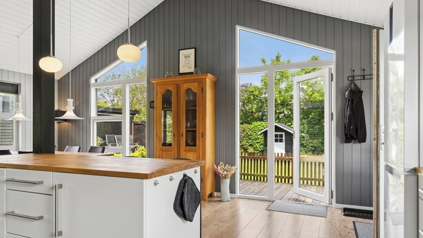 A modern kitchen with a wooden countertop, white cabinets, and a large window. - Peaceful holiday dream by the Limfjord coast (Struer)