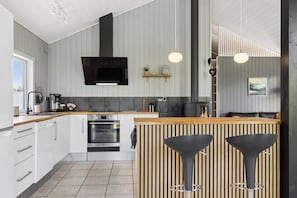 Eine moderne Küche mit einer zentralen Kochinsel, Barhocker und einer hängenden Leuchte.