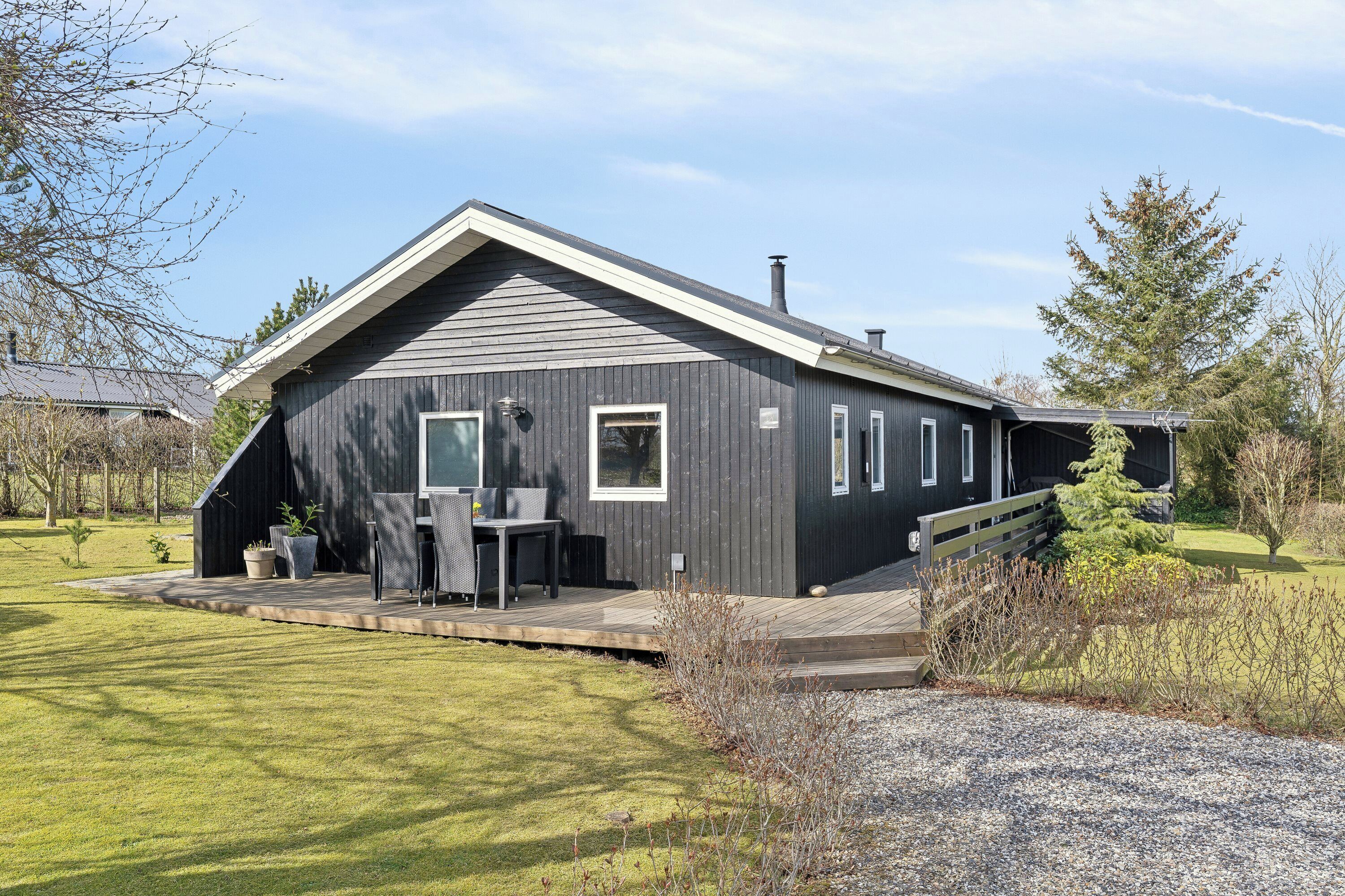 A modern house with a deck, a chimney, and a well-maintained lawn.