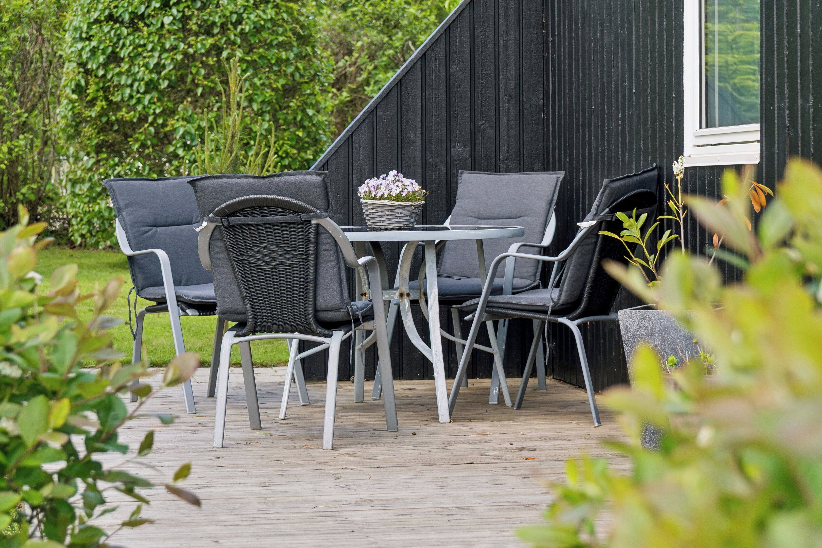 Une terrasse avec une table et des chaises, une plante en pot et une plateforme en bois.