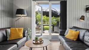 A modern living room with leather sofas, a coffee table, and a sliding glass door leading to an outdoor patio. - Peaceful holiday dream by the Limfjord coast (Struer)