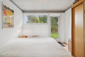Ein Schlafzimmer mit einem großen Bett, einem Fenster, einer Tür und einem Poster an der Wand.