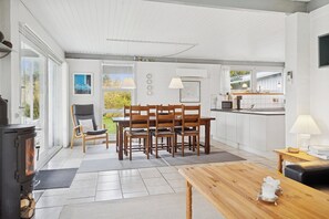 Une cuisine moderne avec un coin repas, un poêle à bois et une vue sur l’extérieur.