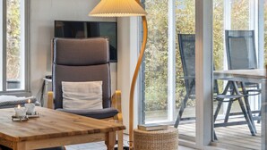 Un salon moderne avec une table basse en bois, un fauteuil confortable, un lampadaire et un téléviseur.