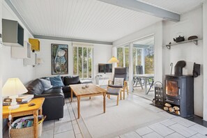 Un salon moderne avec un canapé, une table basse et des fauteuils, une cheminée et une grande fenêtre.