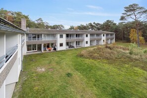 Un immeuble à plusieurs étages, doté d’un toit plat, de grandes fenêtres et d’une cour verdoyante.