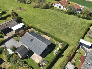 An aerial view of a residential area with houses, a large green lawn, and a paved driveway.